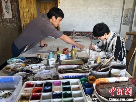 圖為2020年8月下旬，敦煌“80后”畫家張杰龍(左)在為云南麗江“學(xué)生”莫北講解敦煌壁畫的繪畫技巧?！●T志軍 攝
