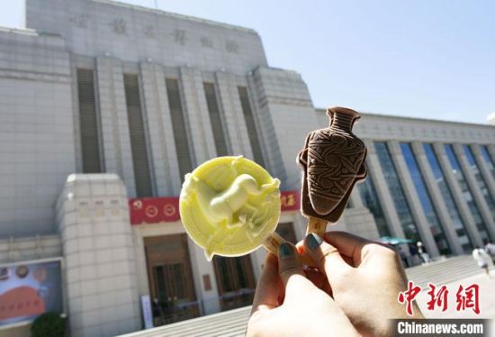 2021年7月30日，游客手拿“銅奔馬”“彩陶瓶”造型的雪糕，在甘肅省博物館前拍照打卡?！「哒?攝