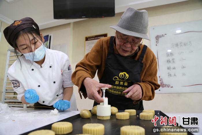 當日，受邀參加活動的臺胞臺屬代表、兩岸婚姻及子女、在甘臺商代表等歡聚一堂。圖為77歲的在甘臺胞潘天鑒制作月餅。九美旦增 攝