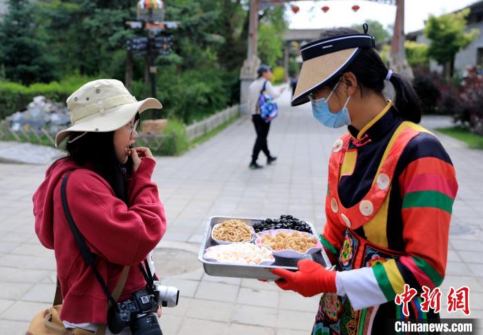 圖為身穿土族服飾的女性介紹當(dāng)?shù)靥厣〕?。　薛?攝