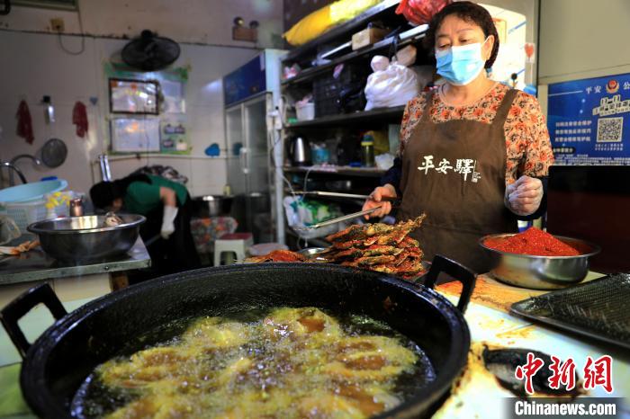 圖為平安驛·河湟民俗文化體驗(yàn)地內(nèi)的商戶炸干板魚?！⊙Φ?攝