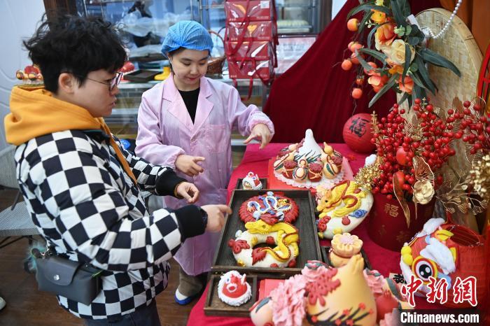 1月25日，隨著春節(jié)臨近，蘭州一花饃店“龍”元素花饃熱銷。圖為工作人員向顧客推薦“龍”元素花饃。九美旦增 攝</p><p>