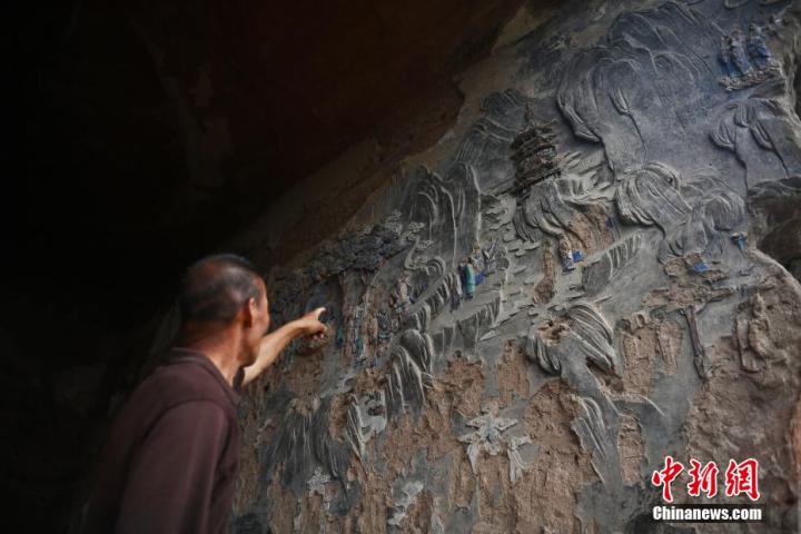7月15日，甘肅省平?jīng)鍪袥艽h百里石窟長廊羅漢洞石窟內(nèi)，該窟文保員郭建平介紹窟內(nèi)石刻彩繪壁畫。郭建平家中三代人曾自發(fā)保護羅漢洞石窟。羅漢洞石窟遺存40余個窟龕，以北魏至清代風(fēng)格為主。中新社記者 李亞龍 攝