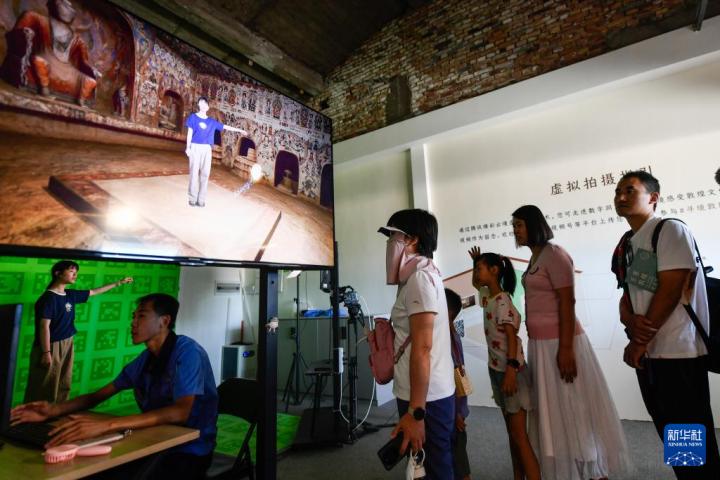 7月22日，游客體驗(yàn)“尋境敦煌——數(shù)字敦煌沉浸展”后，在虛擬演播廳拍攝一段真人與洞窟虛擬場(chǎng)景交互的視頻。新華社記者 郎兵兵 攝</p>
<p>